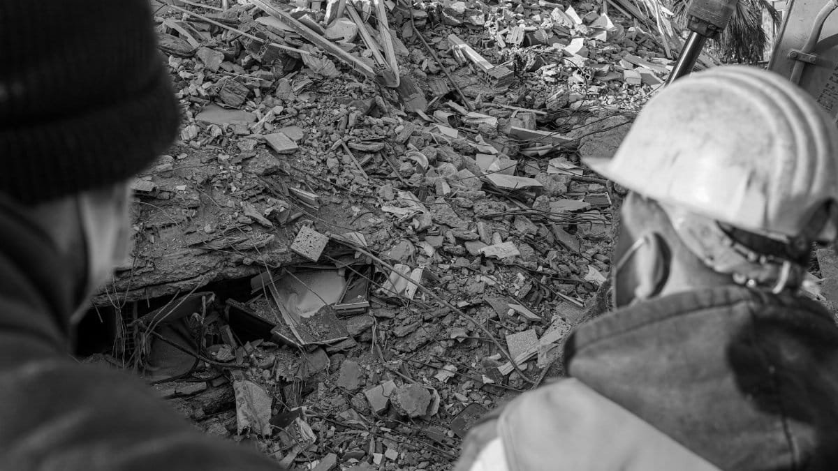 A rescue team examines earthquake debris in Kahramanmaraş, Turkey, highlighting disaster impact.