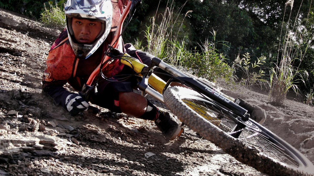 Close-up of a cyclist crashing on a dirt mountain bike track, showing action and speed.