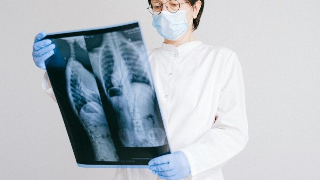 A doctor in protective gear analyzing an X-ray scan indoors.