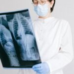 A doctor in protective gear analyzing an X-ray scan indoors.