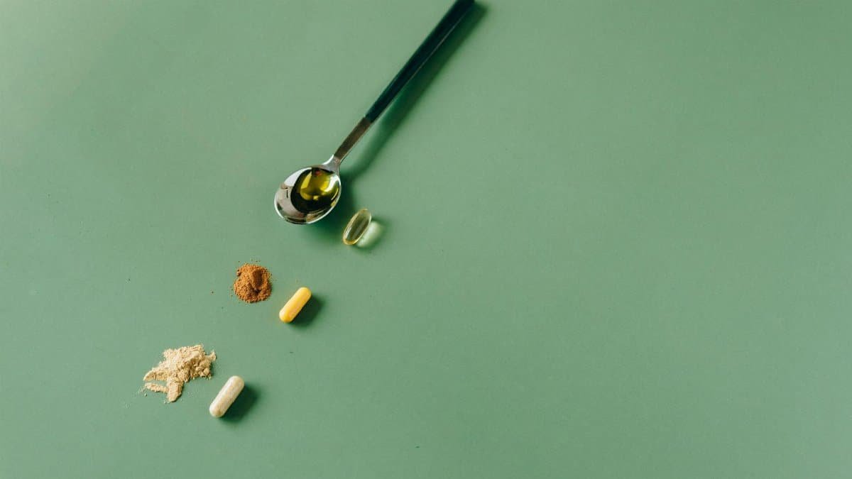 Assorted herbal supplements and powders on a green backdrop with a spoon.