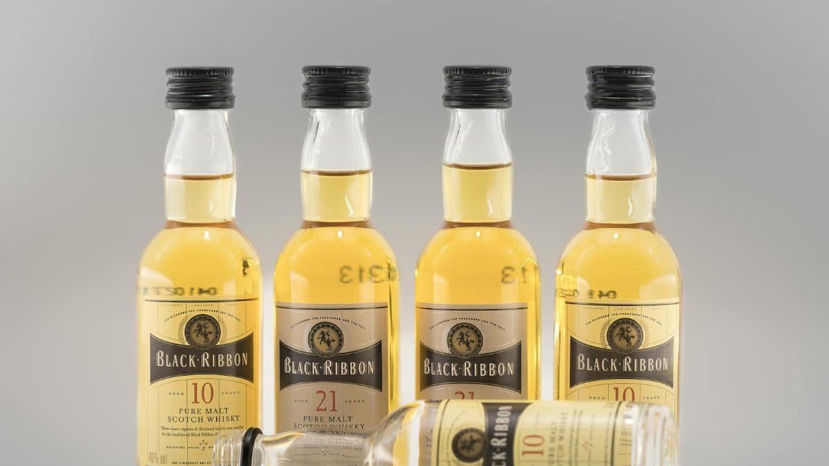 Five Black Ribbon whiskey bottles with a gray background, ideal for product advertisements.