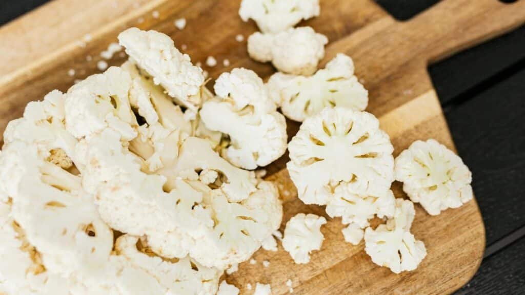 Slices of fresh cauliflower on a wooden cutting board, perfect for cooking and healthy recipes.