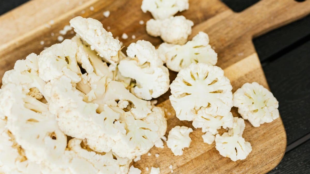 Slices of fresh cauliflower on a wooden cutting board, perfect for cooking and healthy recipes.