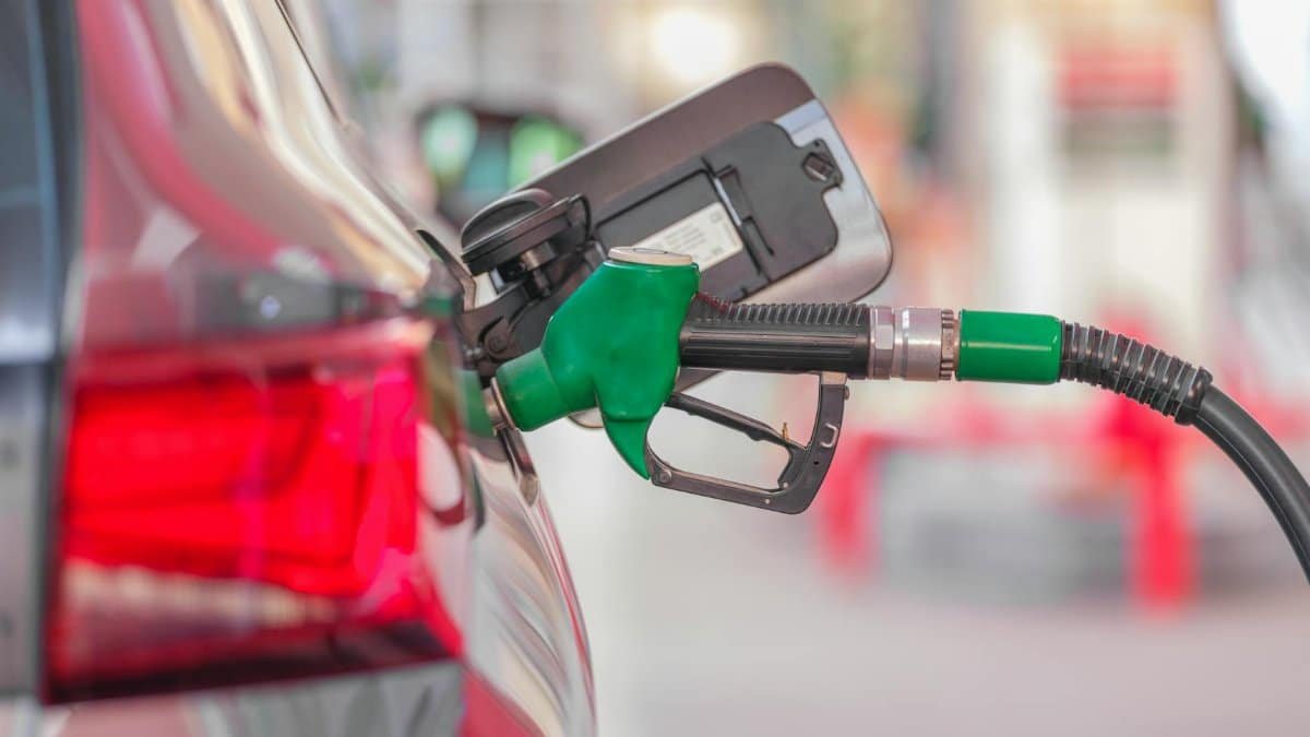 A close-up view of a fuel pump nozzle inserted into a car's tank at a gas station.