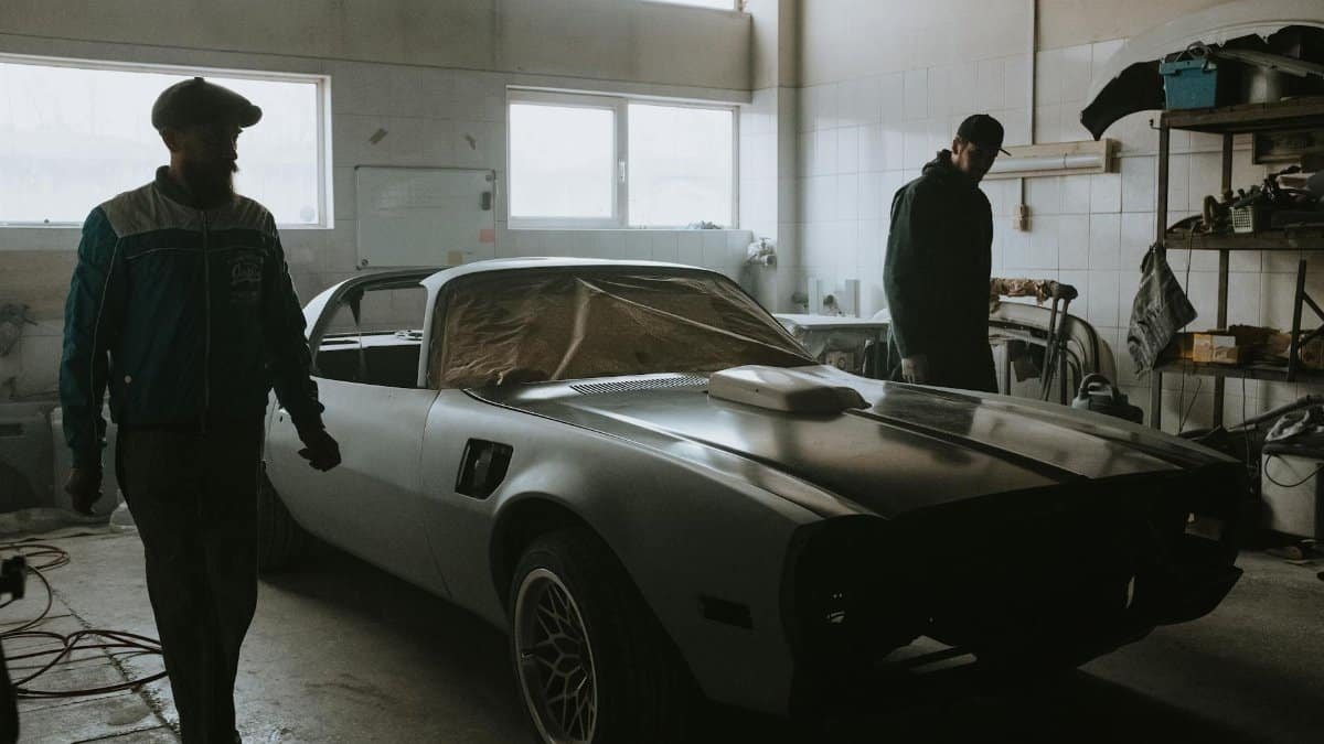 Mechanics working on a vintage car restoration in a dimly lit garage, capturing the essence of classic automotive care.