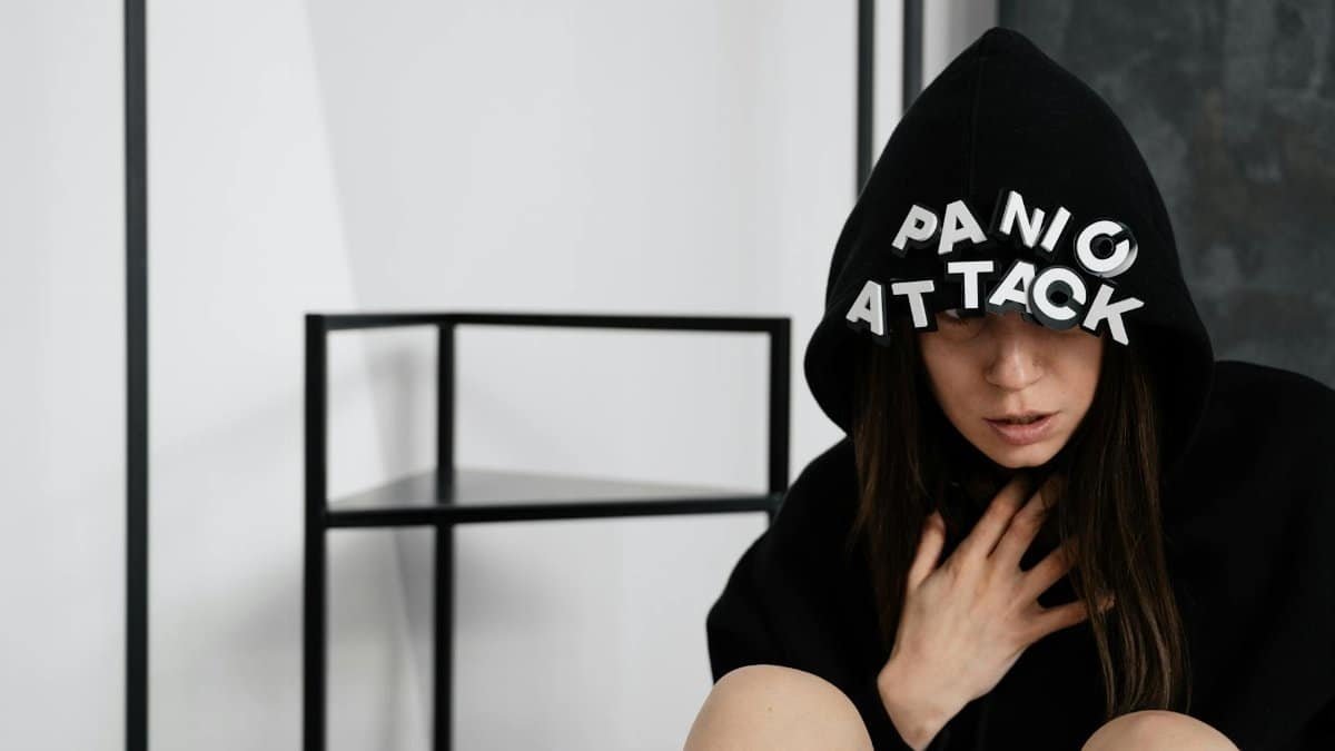 A woman in a hoodie with panic attack letters, representing mental health struggles.