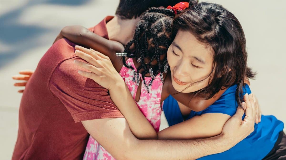 A diverse family shares a heartfelt hug outdoors, symbolizing love and unity.