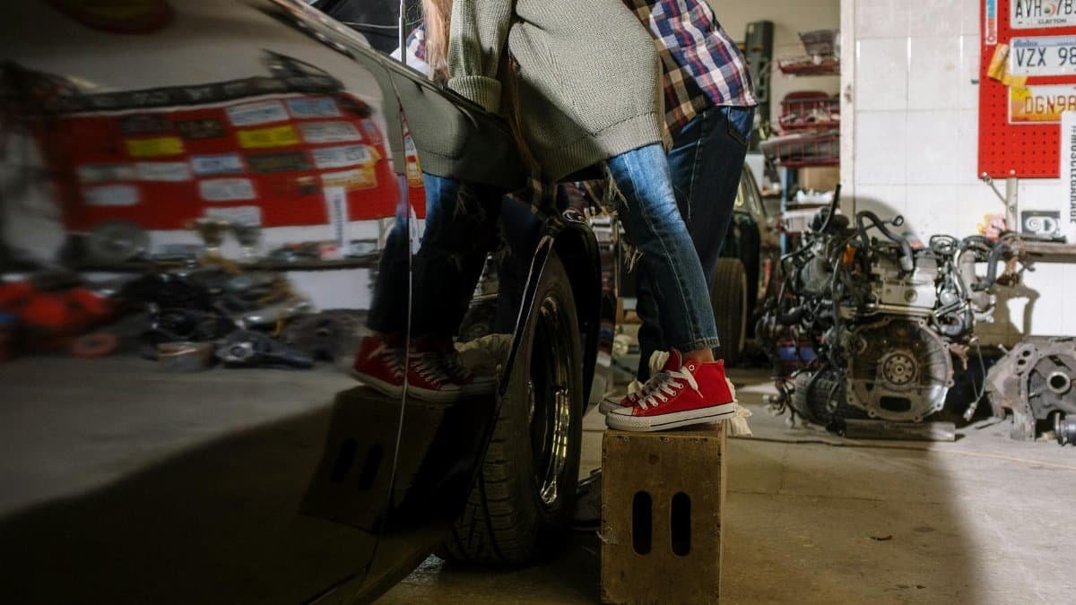 A father and daughter bonding while working on a car in a repair shop, showcasing teamwork and family.