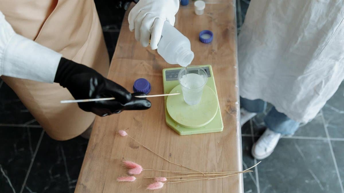 Detailed shot of mixing chemicals into a plastic cup using a measuring stick.