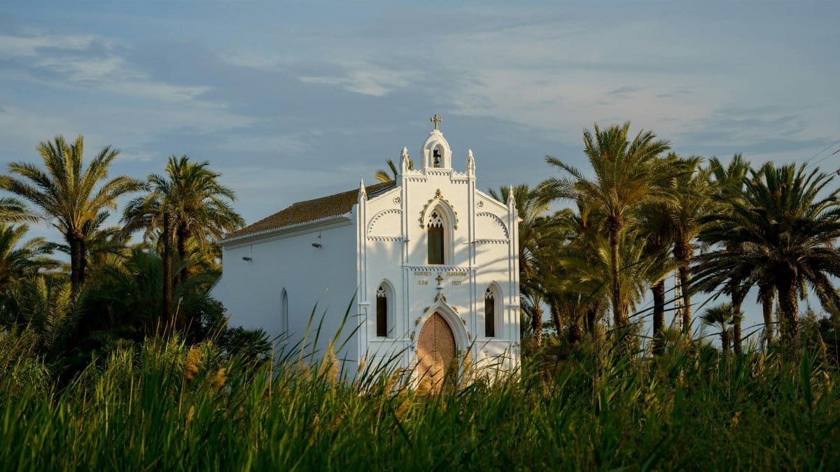 Stunning gothic revival church with palm trees and lush greenery in Valencia, Spain.