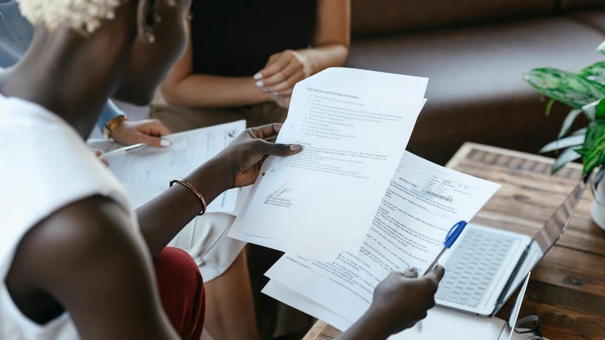 From above of crop anonymous African American female comparing data in papers at table of office