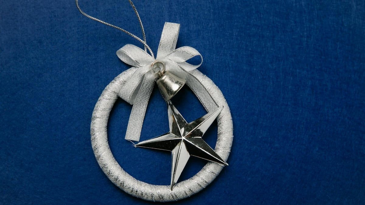 Silver star ornament with a bow, perfect for festive decoration on blue background.