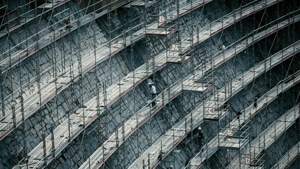 Detailed view of scaffolding on a massive construction site with workers.