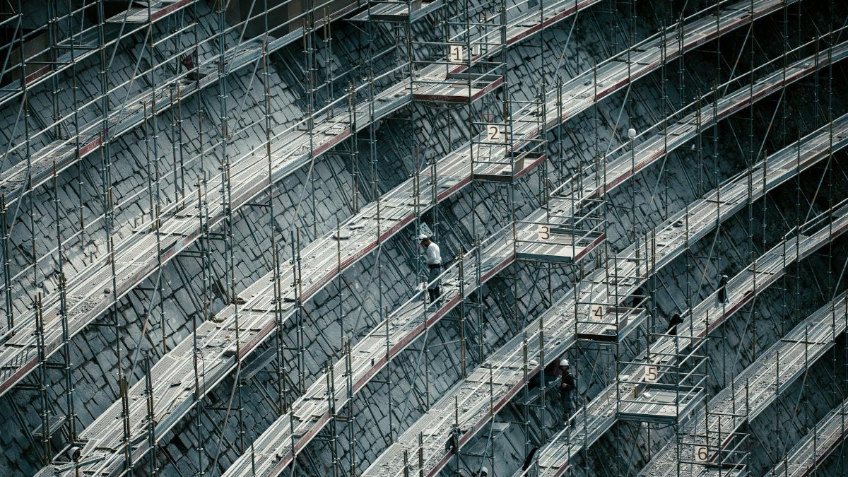 Detailed view of scaffolding on a massive construction site with workers.