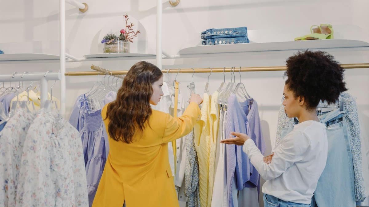Two women browsing clothing in a stylish boutique, exploring various fashion options.
