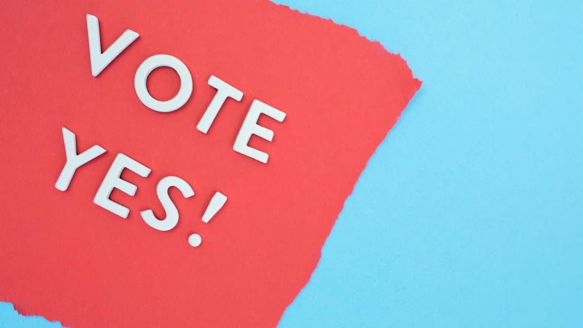 Creative image of the phrase 'Vote Yes!' on a torn red paper against a blue background.