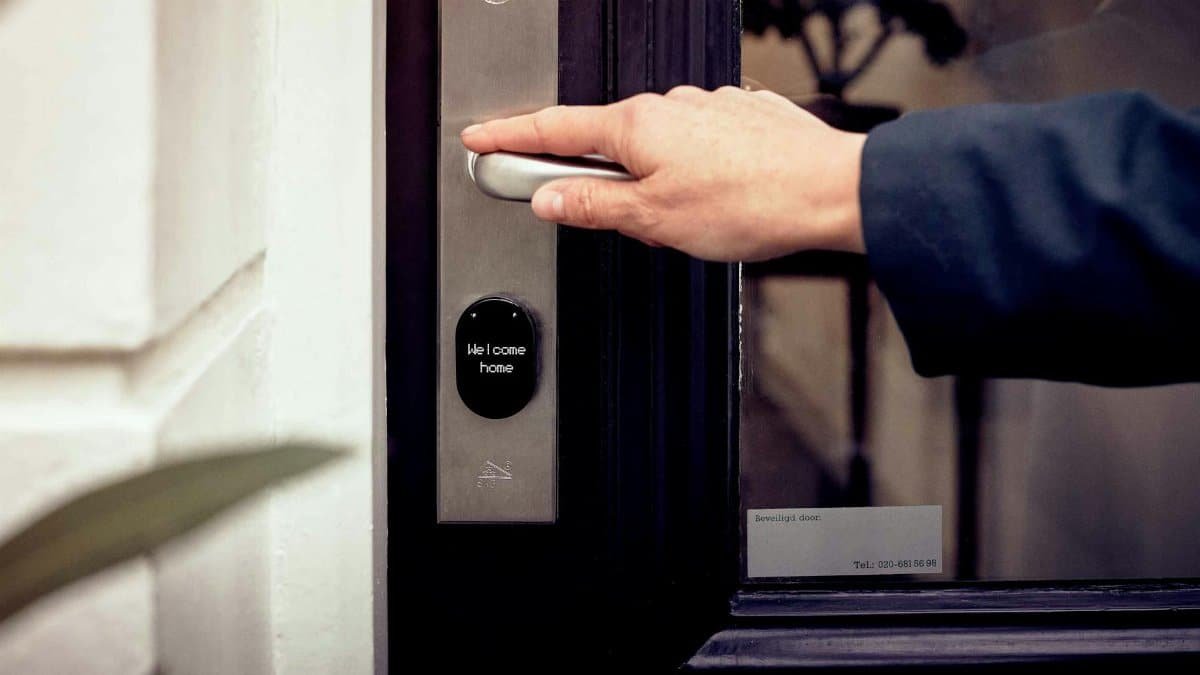 A hand opening a smart home door with digital access panel, conveying security and technology.