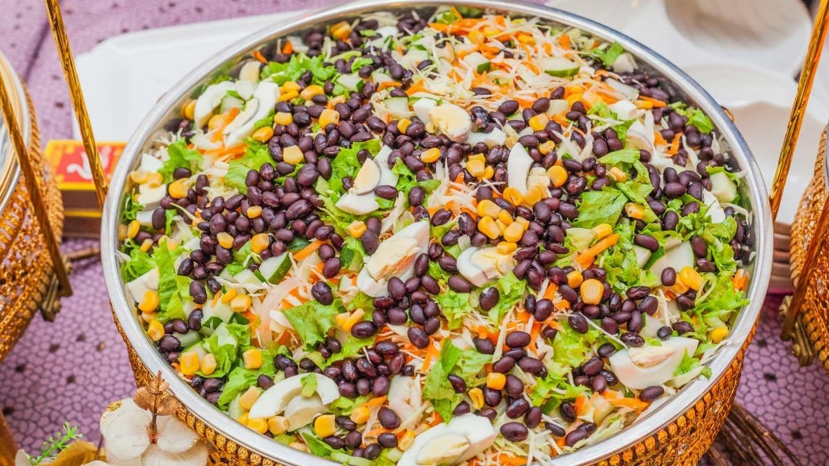 Colorful salad with black beans, corn, and cabbage mix in a decorative brass bowl.