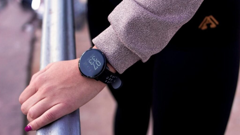 A close-up shot of a hand wearing a digital smartwatch, showcasing modern wearable technology outdoors.
