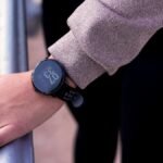 A close-up shot of a hand wearing a digital smartwatch, showcasing modern wearable technology outdoors.