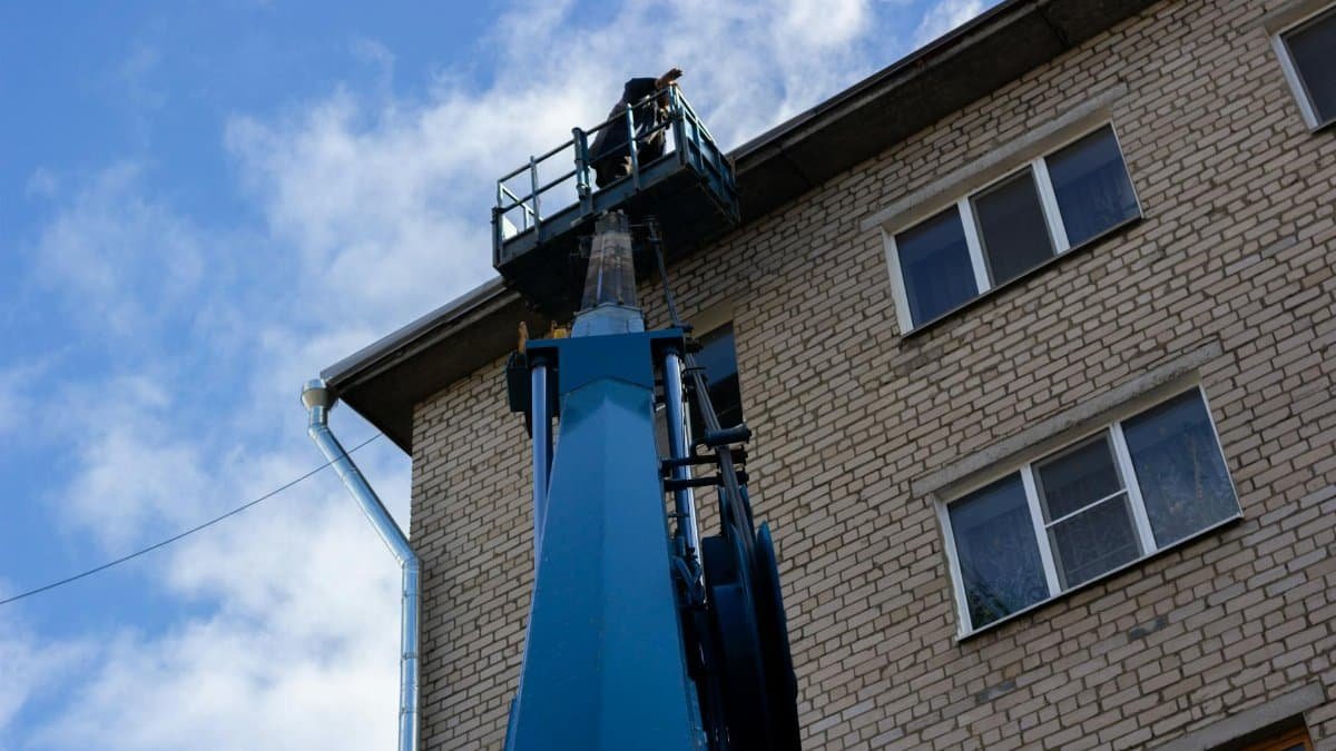Low angle shot of a brick building exterior with a construction crane reaching the roof.