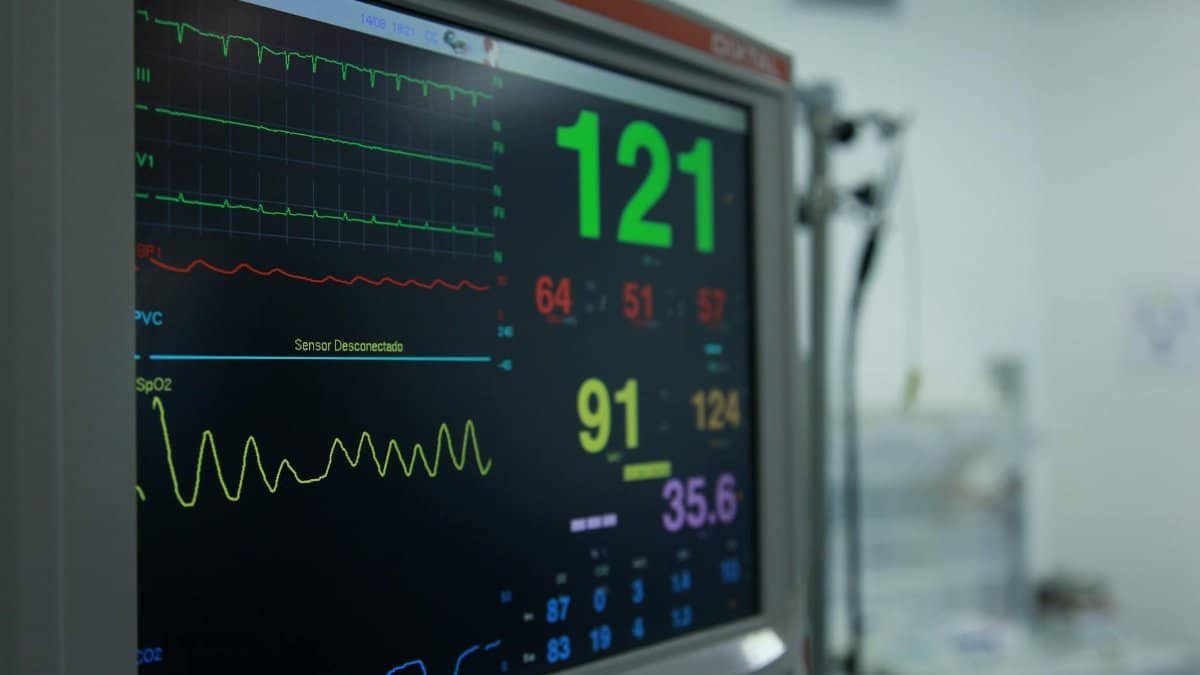 Close-up view of a vital signs monitor showing various medical readings in a hospital setting.