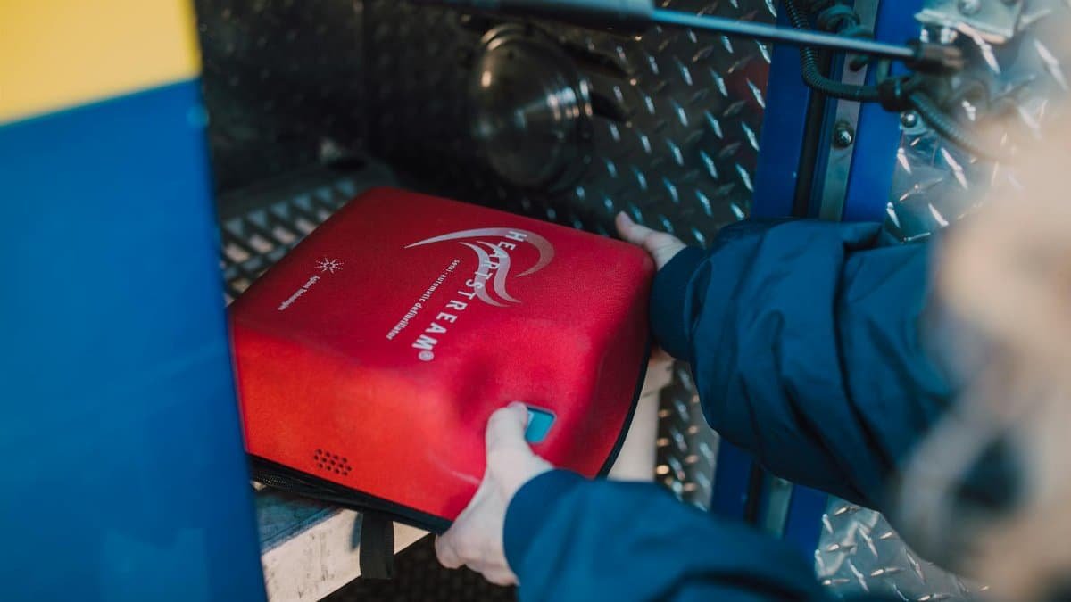 Close-up of an emergency defibrillator being placed in a fire truck compartment.