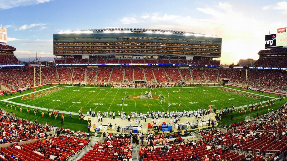 A stunning panoramic shot of Levi's Stadium in Santa Clara during a packed football game at sunset.