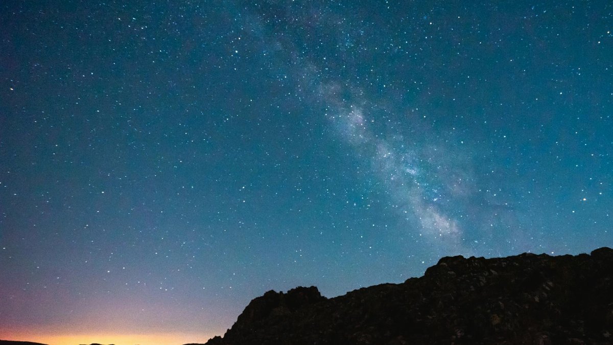 Beautiful view of the Milky Way in a clear starry sky over a silhouetted landscape.