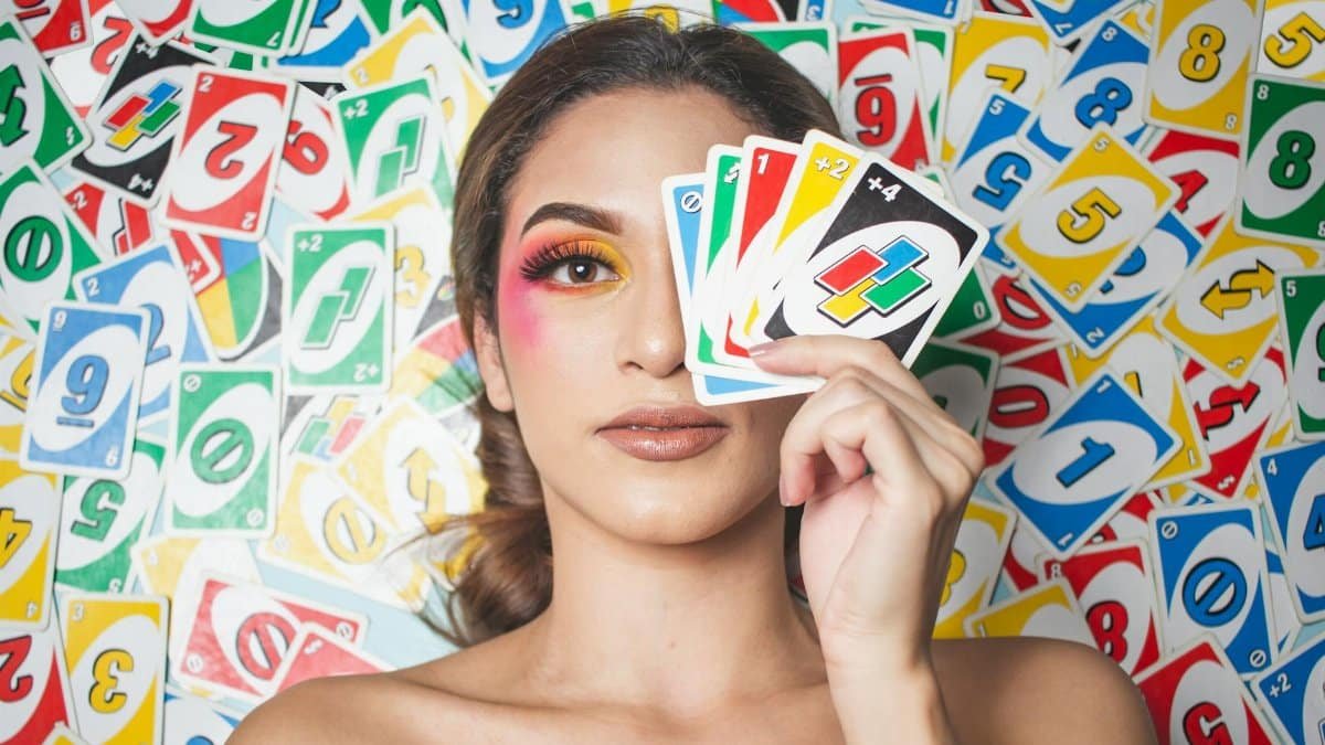 Vibrant portrait of a woman holding UNO cards with bold makeup and a playful expression.