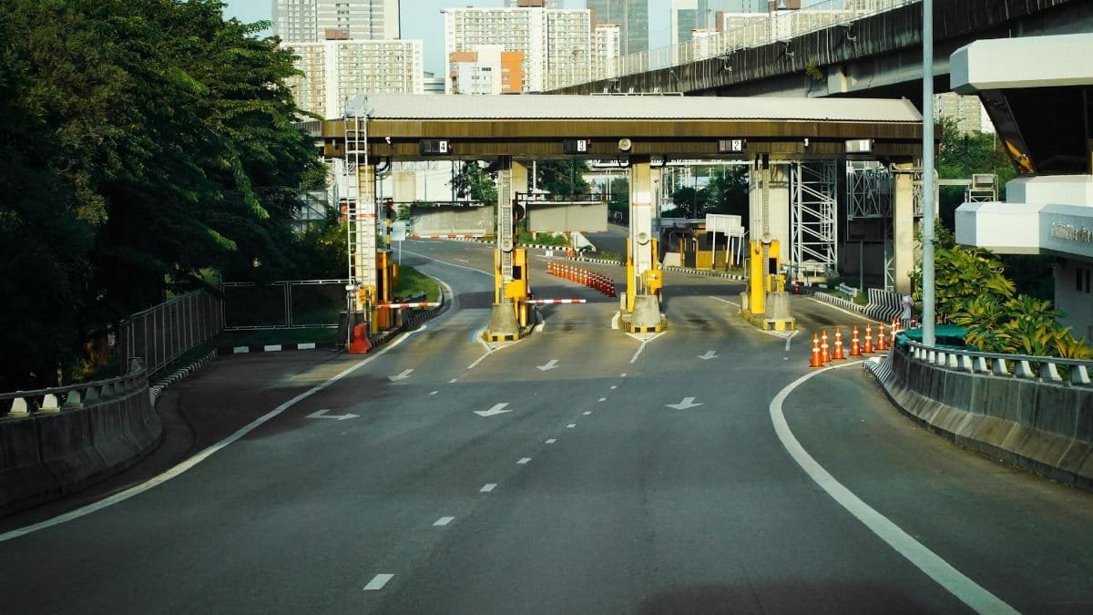 Toll booth on a Bangkok highway with urban skyscrapers in the background, during a clear day.