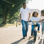 Happy family teaching their child to cycle on a sunny day outdoors.