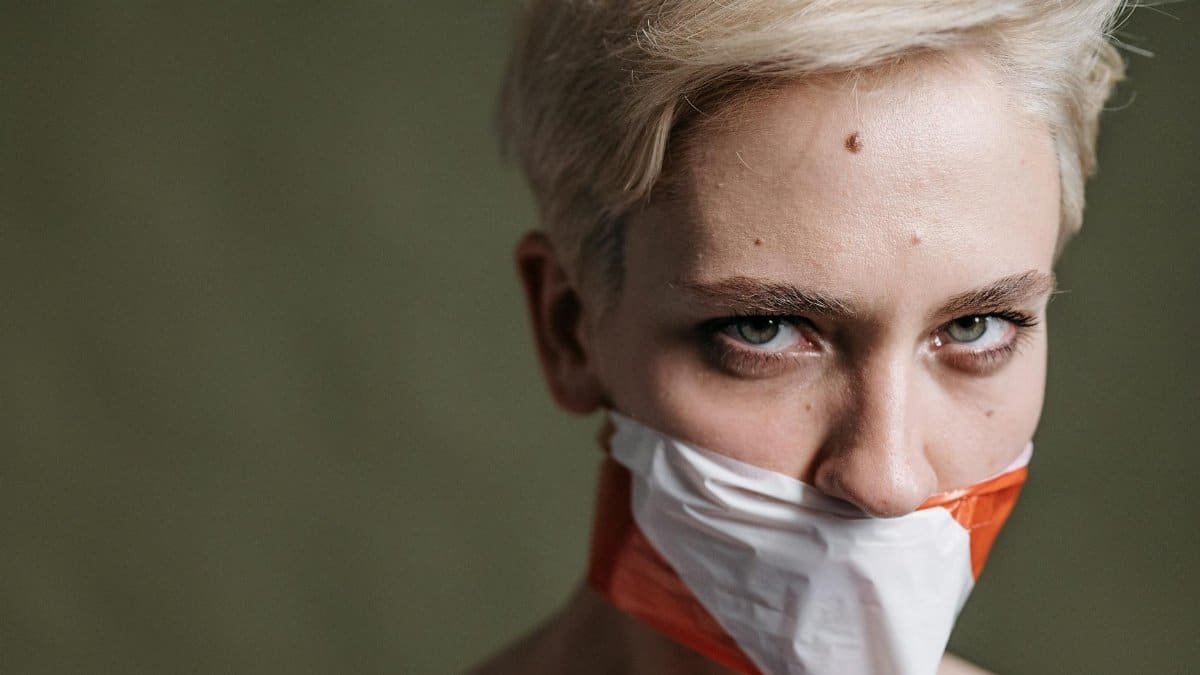 A defiant woman with taped mouth symbolizes silenced voices and human rights.