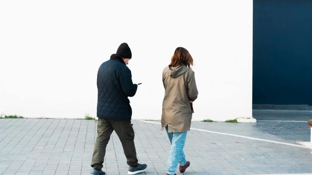 Two adults walking by a white wall in İstanbul, showcasing urban street fashion and daily life.