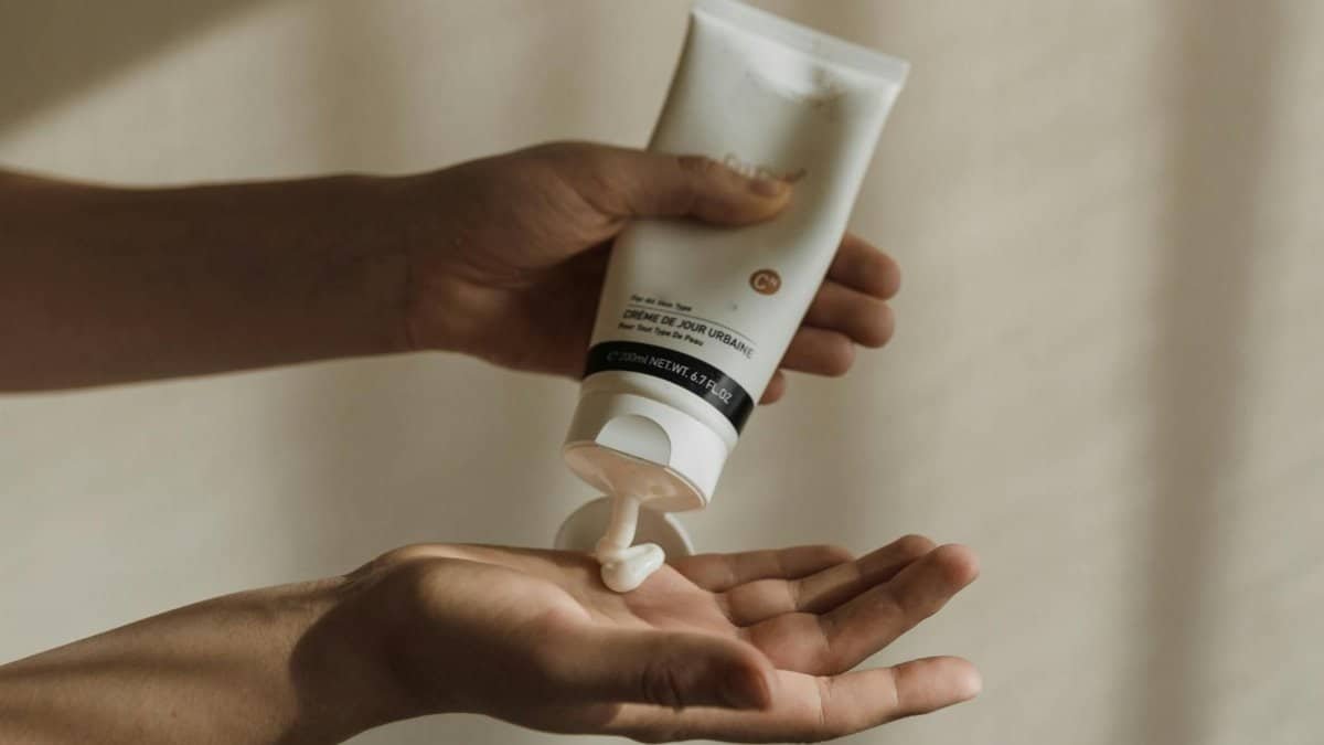 Close-up of a woman squeezing lotion onto her hand, emphasizing skincare and self-care routine.
