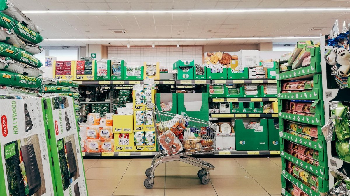 Shopping cart in a vibrant supermarket aisle in Padova, Italy.