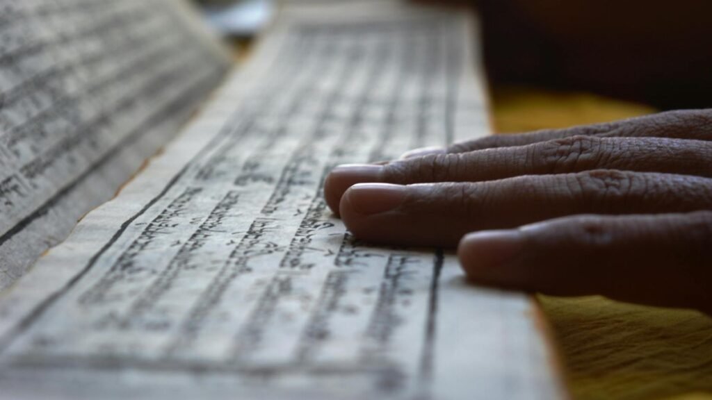 Hands gently rest on Buddhist scripture in Sikkim, reflecting spiritual focus and meditation.