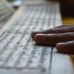 Hands gently rest on Buddhist scripture in Sikkim, reflecting spiritual focus and meditation.