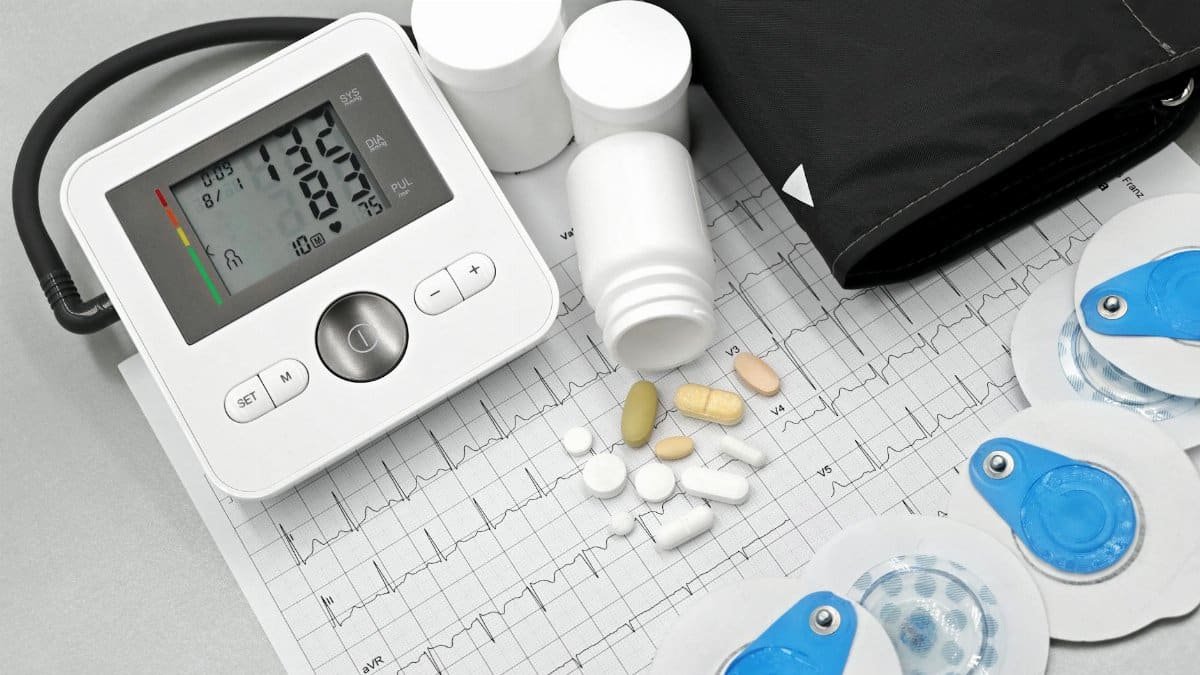 Flat lay of blood pressure monitor, pills, and ECG printout for heart health theme.