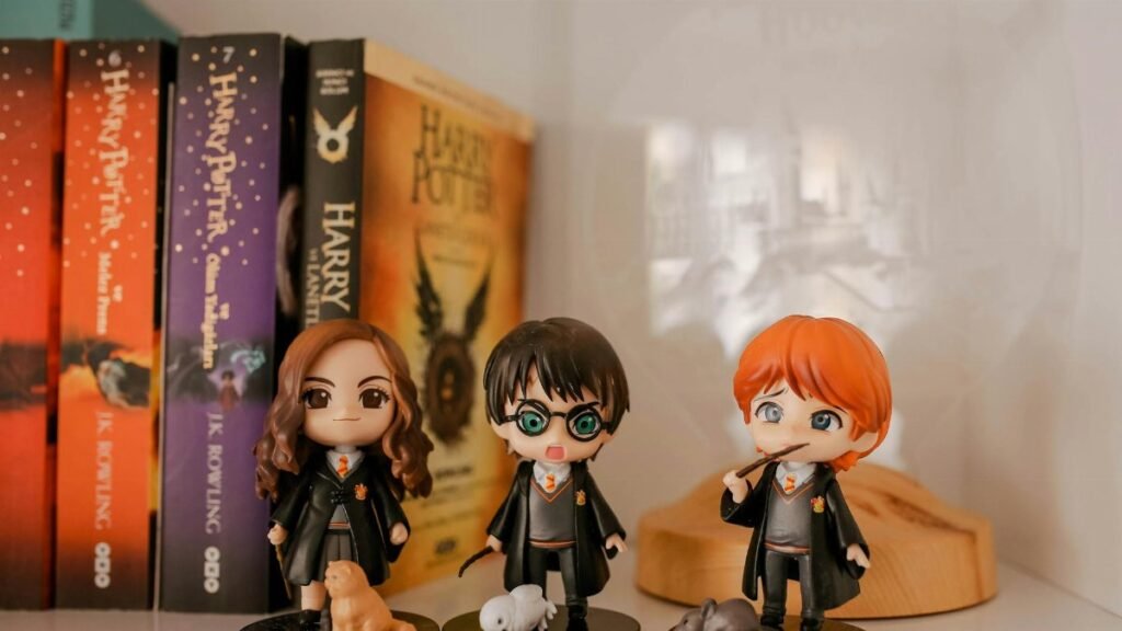 Miniature Harry Potter figurines displayed with book collection on a shelf.