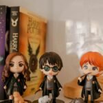 Miniature Harry Potter figurines displayed with book collection on a shelf.