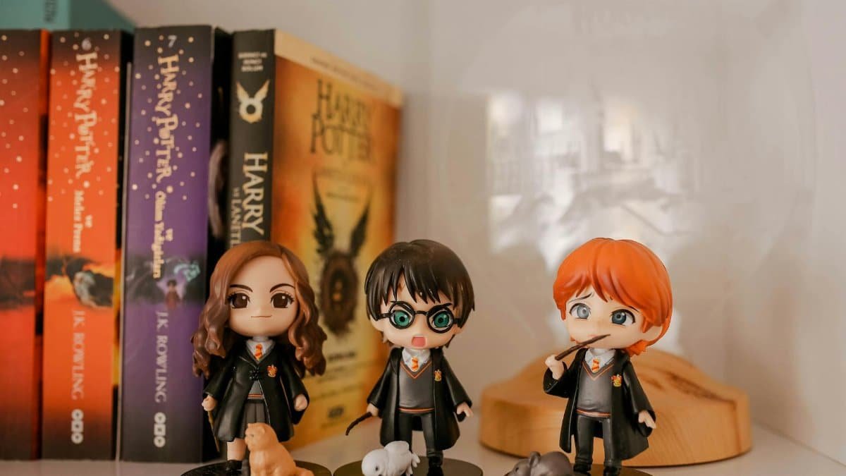 Miniature Harry Potter figurines displayed with book collection on a shelf.