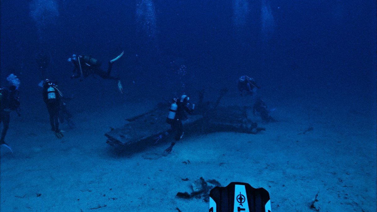 Divers exploring underwater wreckage during a deep ocean scuba dive.
