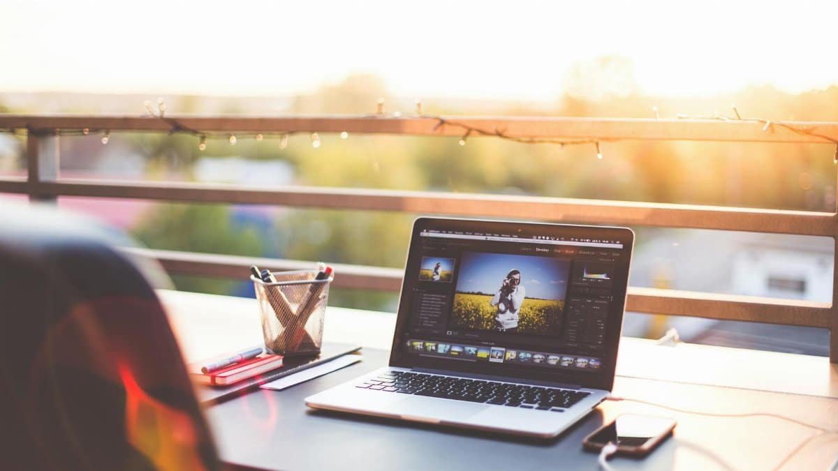A modern workspace on a balcony with a laptop and smartphone during sunset, capturing a creative work environment.
