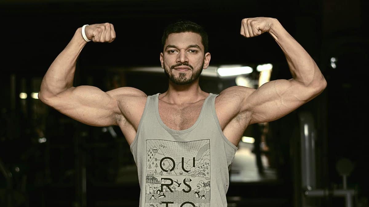 A fit man flexing his biceps in a gym environment, showcasing strength and fitness.