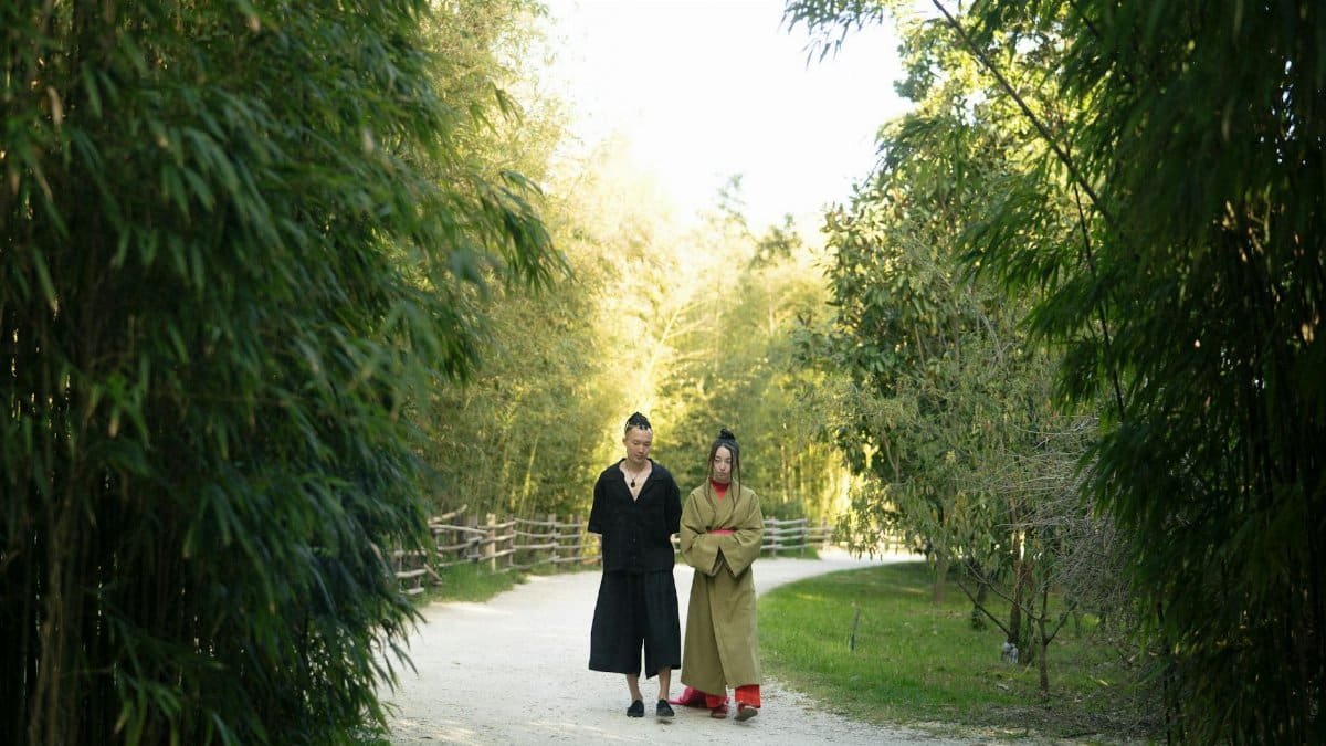 Couple in traditional Japanese attire walking through a peaceful bamboo grove, embracing nature.