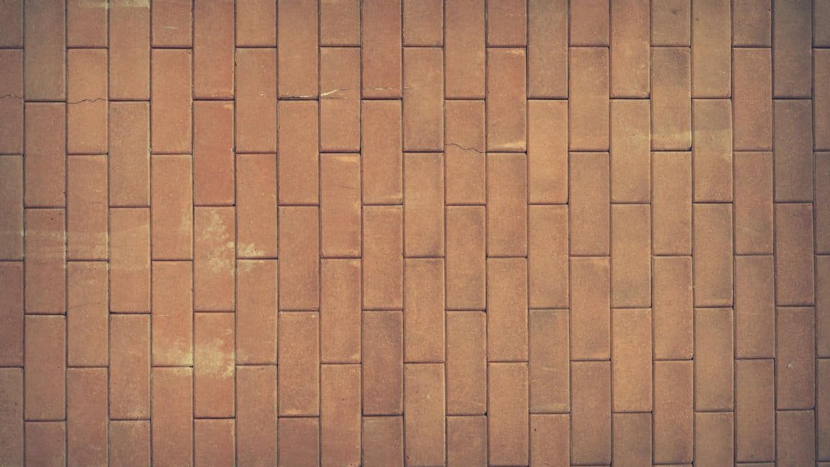 A vintage red brick wall texture serves as a classic background with rich earthy tones.