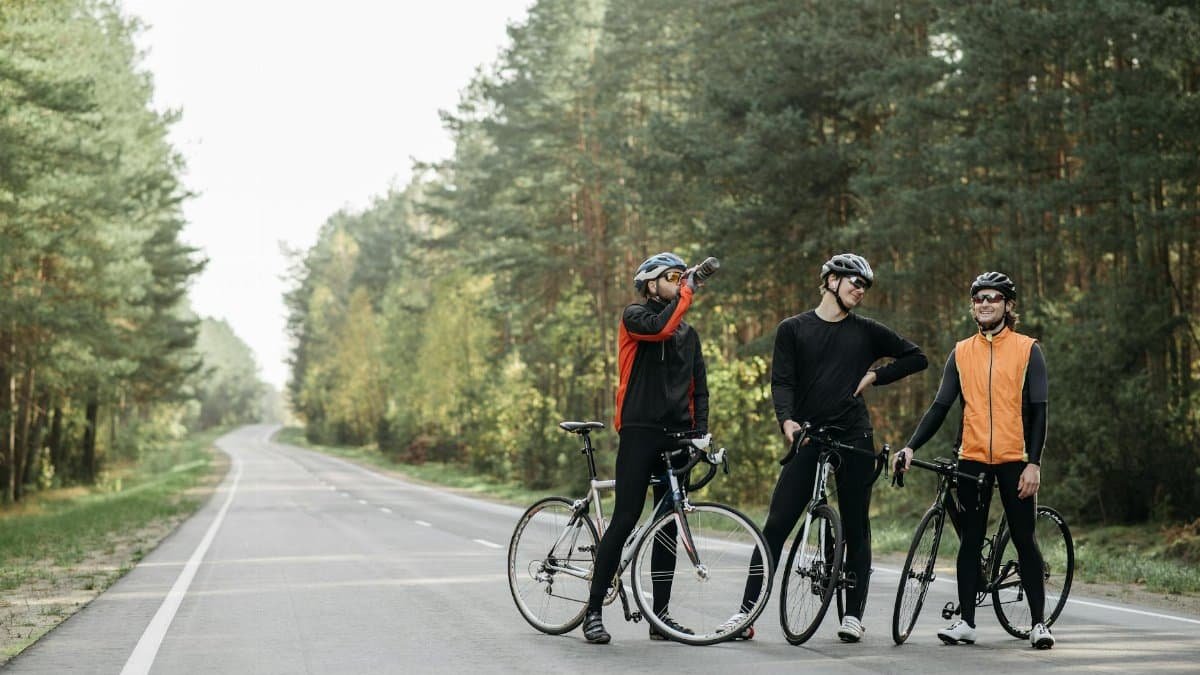 Three cyclists pause for a break in a serene forest setting, enjoying the outdoors.
