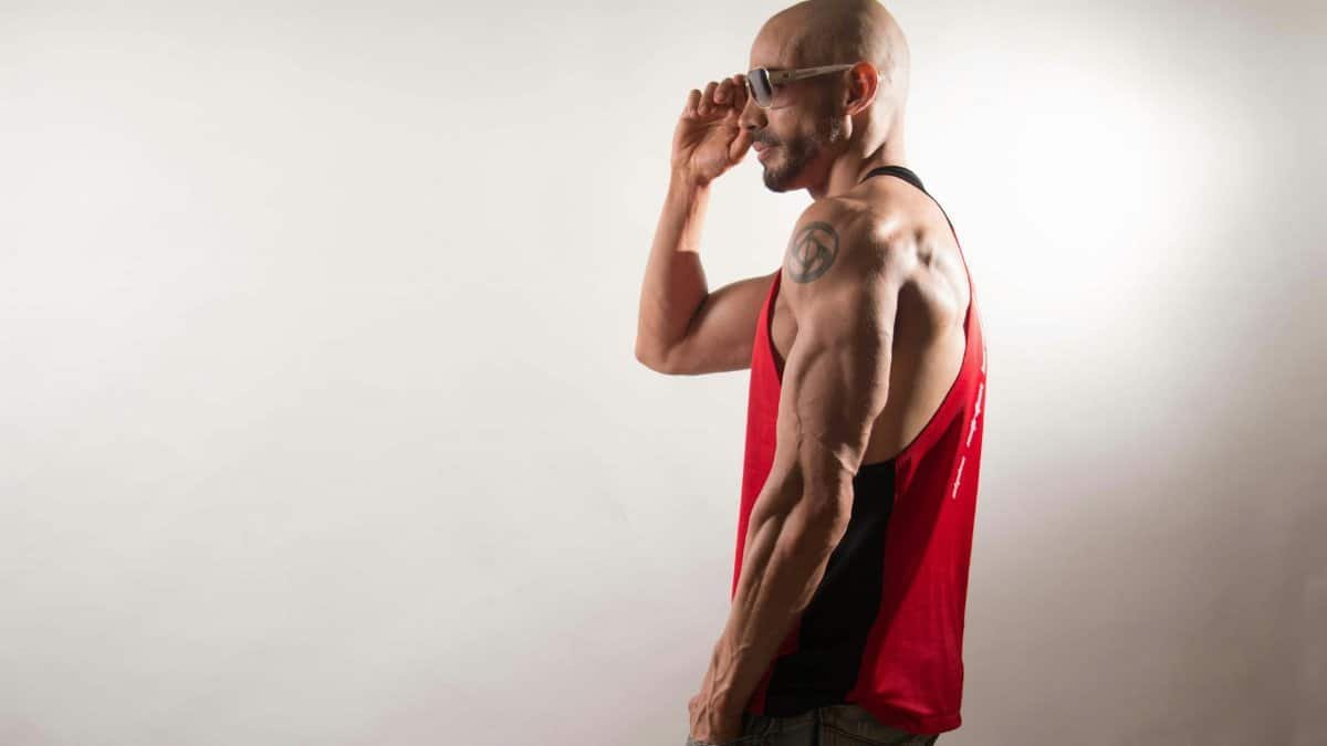 A fit, muscular man posing in studio, showcasing strong triceps.